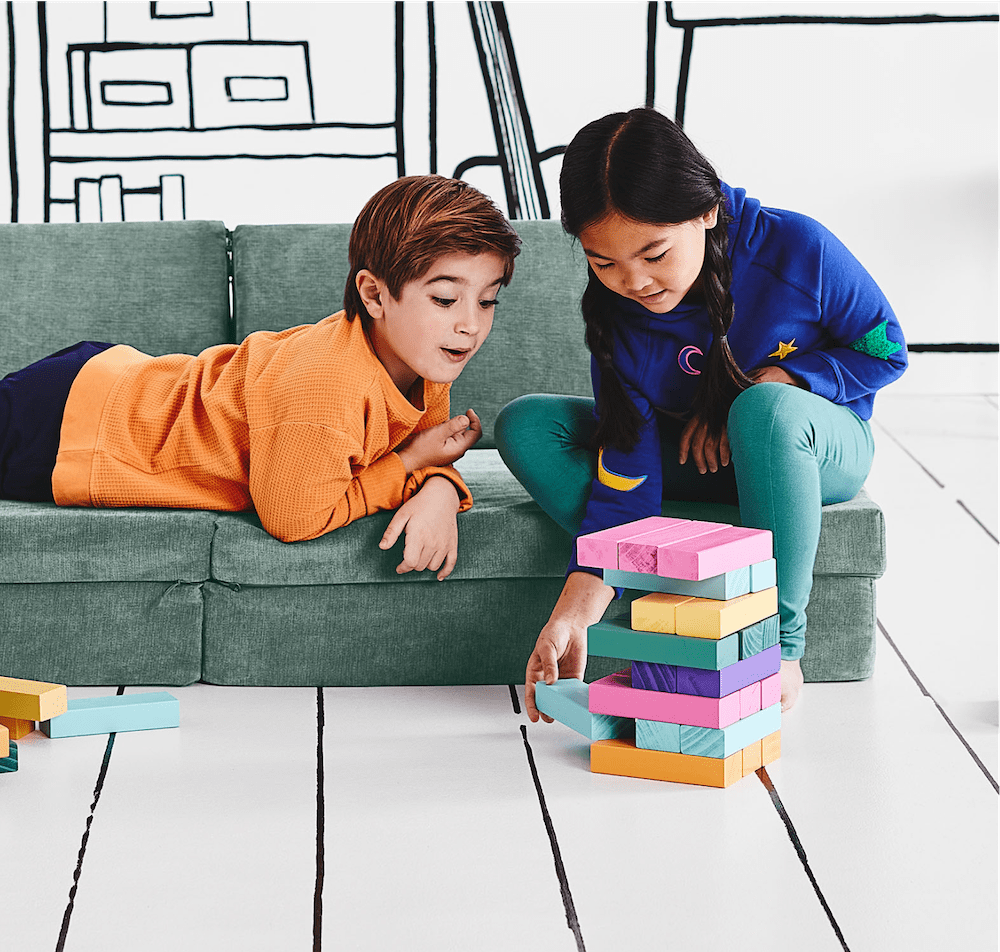 two kids laying on the play couch playing with stackable building blocks.