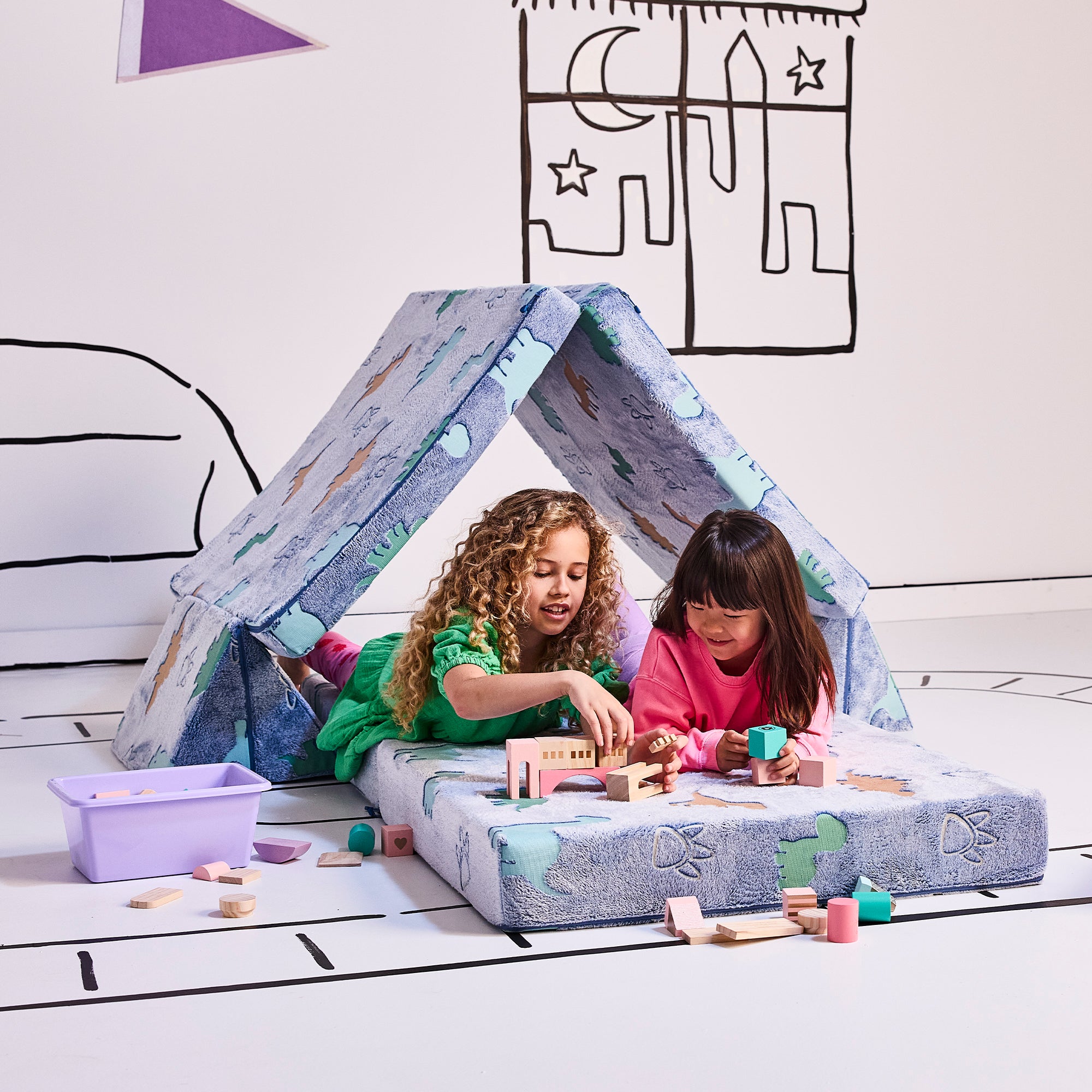 two girls playing with building blocks in the Treacherous Tunnel configuration in the dinosaur color.