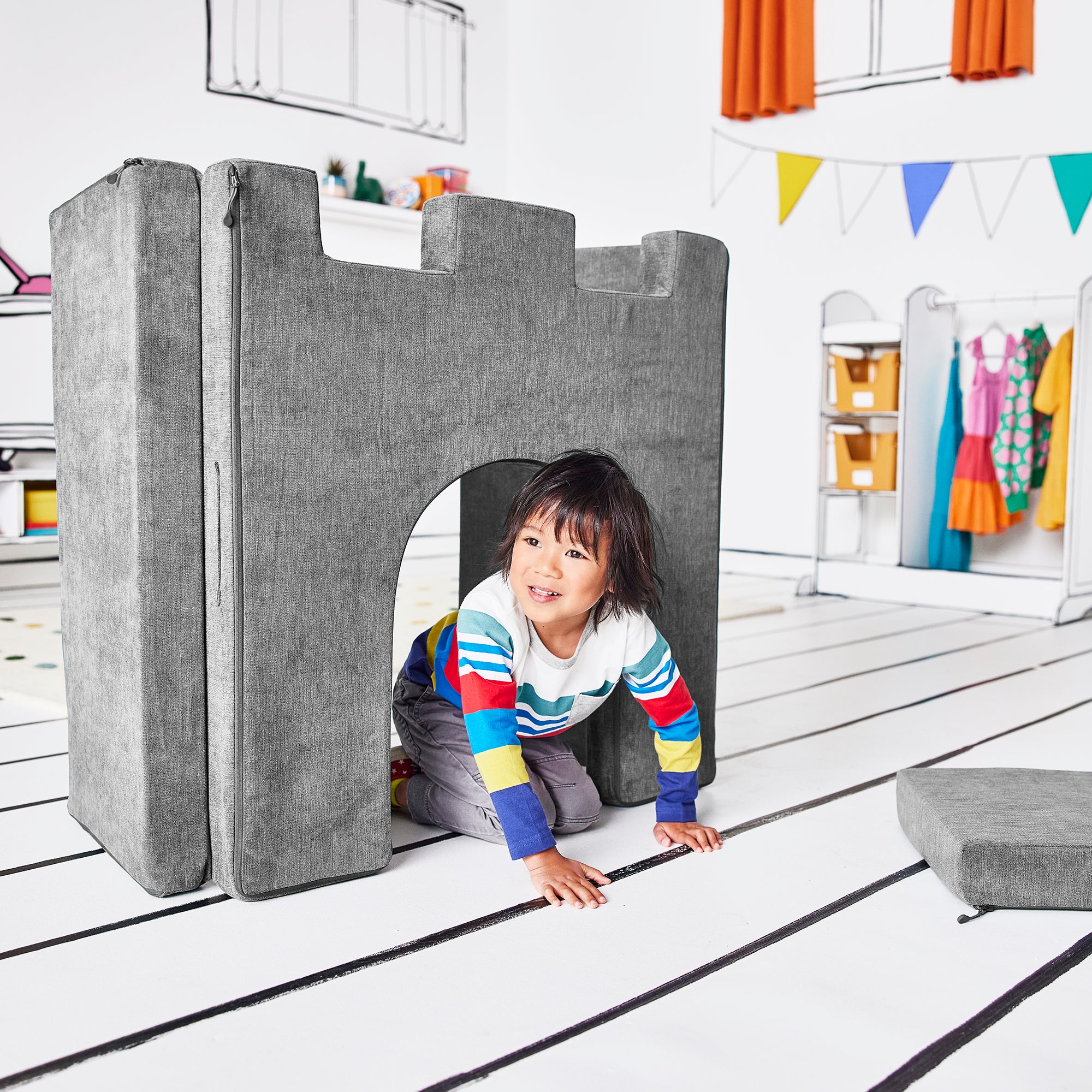 Boy crawling through the arch of the hinged doorway piece of the Yourigami Kids Play Castle in mountain-gray color