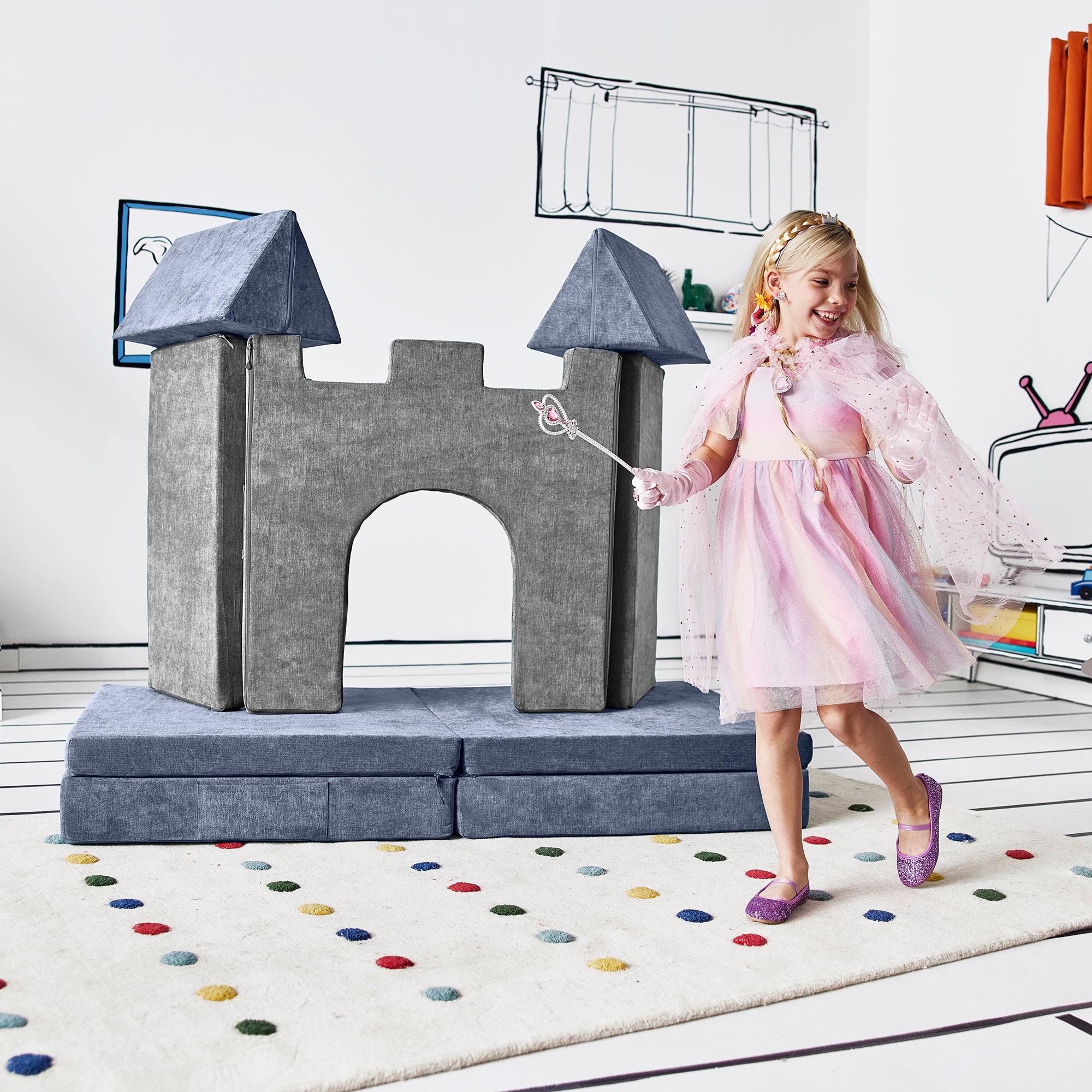 Girl dressed as a princess running past the deluxe castle configuration of the Yourigami Kids Play Castle in mountain-gray color and the Yourigami Kids Play Couch in blue-lagoon color