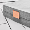 Close-up view of the base hinged panel piece of the Yourigami Kids Play Couch in mountain-gray color with a journal tucked into the stash pocket of the cover