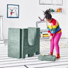Girl preparing to hit a golf ball off the drawbridge piece and through the turrets of the upturned doorway piece of the Yourigami Kids Play Castle in green-meadows color 