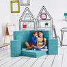 Boy whispering into his friend's ear while they're both sitting on the Rockstar Stage configuration of the Yourigami Kids Play Couch in tropical-teal color