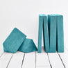 The four modular pieces of the Yourigami Kids Play Couch in tropical-teal color with both hinged panels folded up and the triangle pieces resting on each other