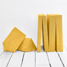 The four modular pieces of the Yourigami Kids Play Couch in sunflower-yellow color with both hinged panels folded up and the triangle pieces resting on each other