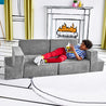 Boy reading a book while reclining on the Lazy Lounger configuration of the Yourigami Kids Play Gym in mountain-gray color