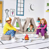 Children pretending to roast marshmallows at a play fire and resting on the Cozy Campsite configuration of the Yourigami Kids Play Fort in beige-sands color