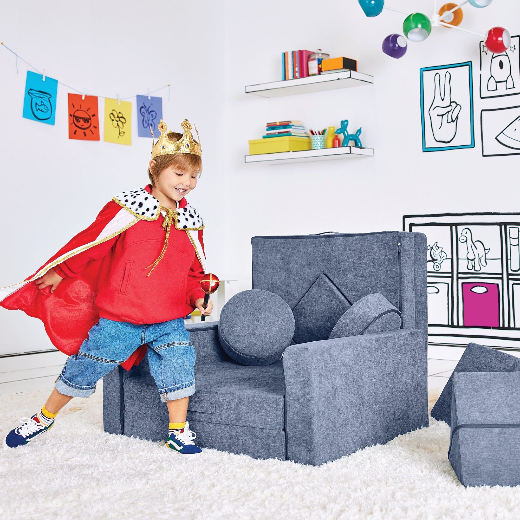 Boy dressed as a king playing by the Royal Throne configuration of the Yourigami Kids Play Fort in blue-lagoon color