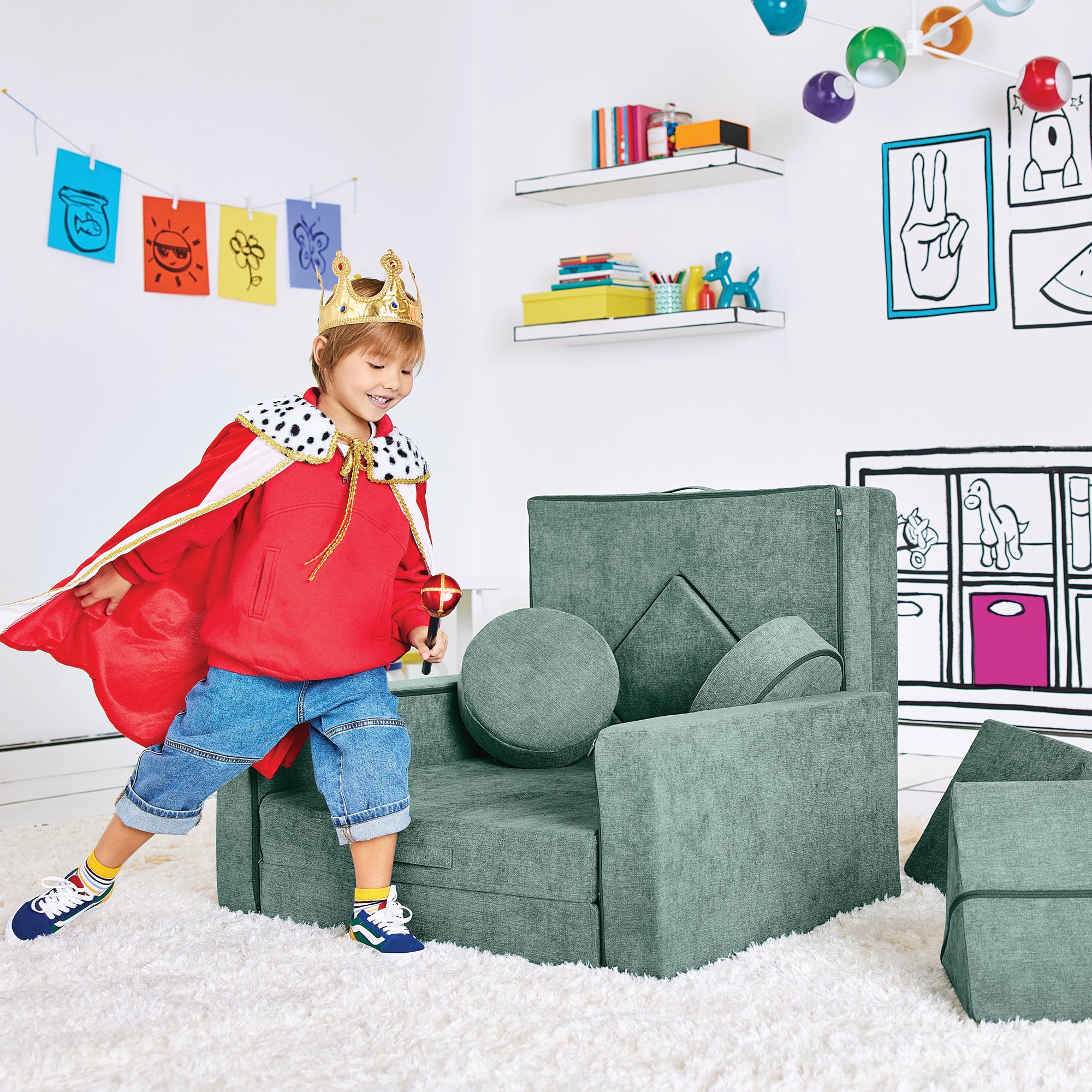 Boy dressed as a king playing by the Royal Throne configuration of the Yourigami Kids Play Fort in green-meadows color