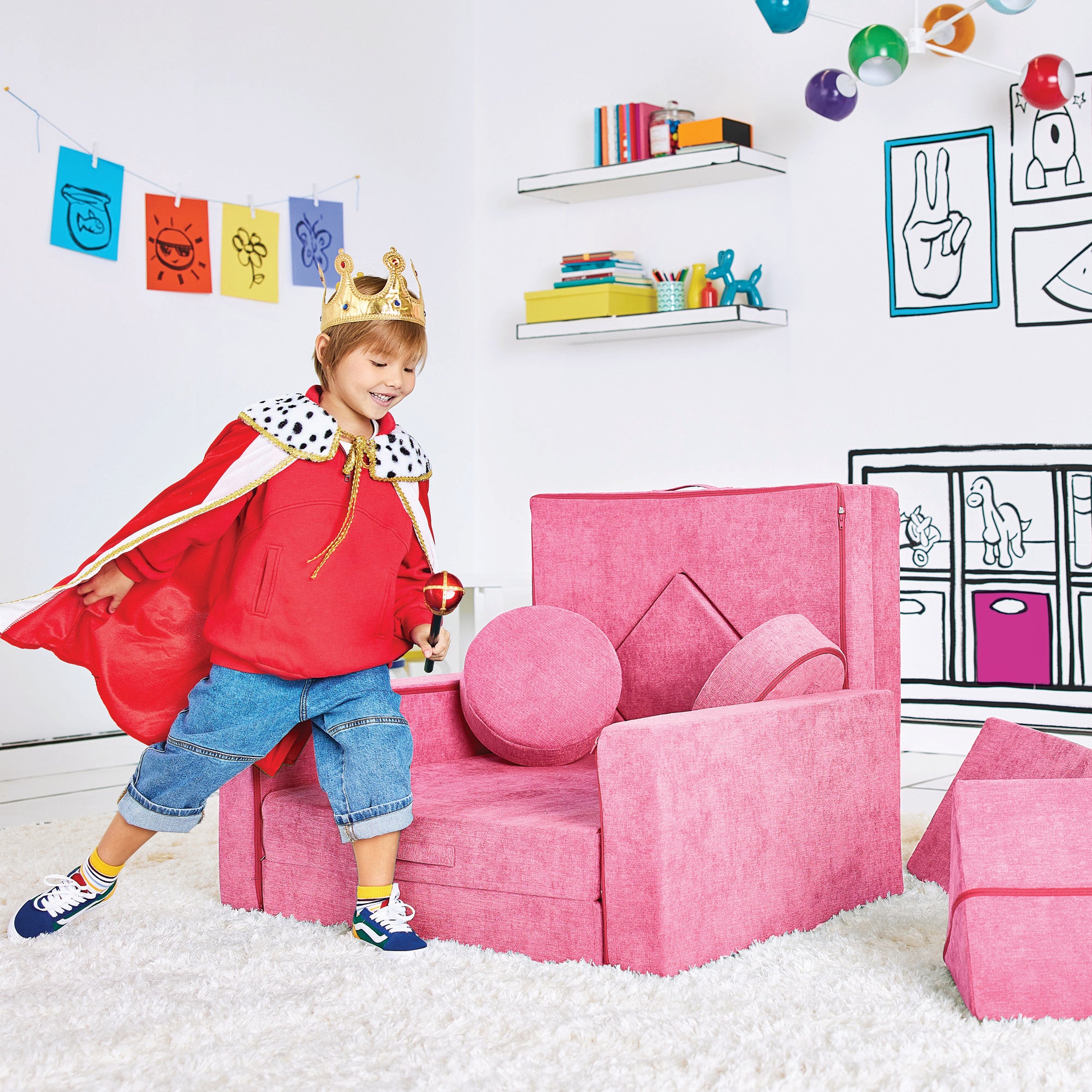 Boy dressed as a king playing by the Royal Throne configuration of the Yourigami Kids Play Fort in himalayan-pink color